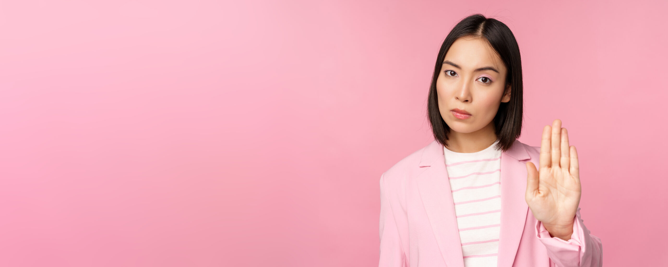 A woman with curly hair wearing a yellow cardigan joyfully spreading her arms outside, looking free and confident in an urban setting.